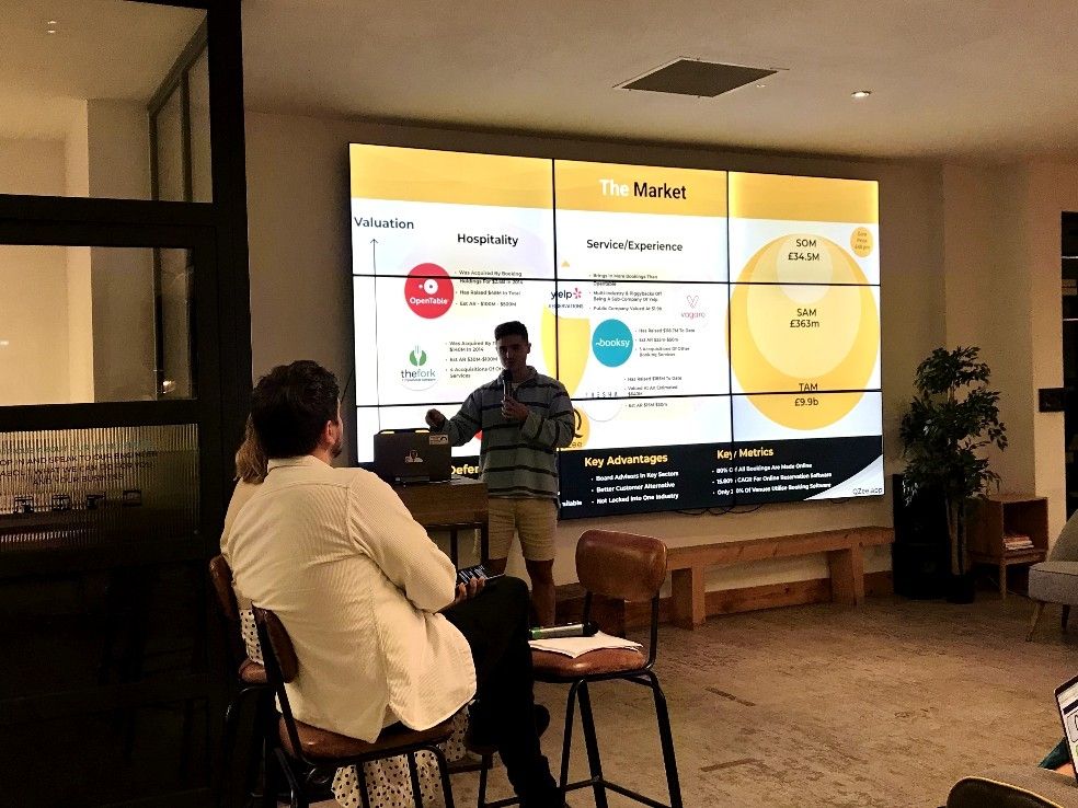 Cameron presenting QZee in front of a historical market analysis slide